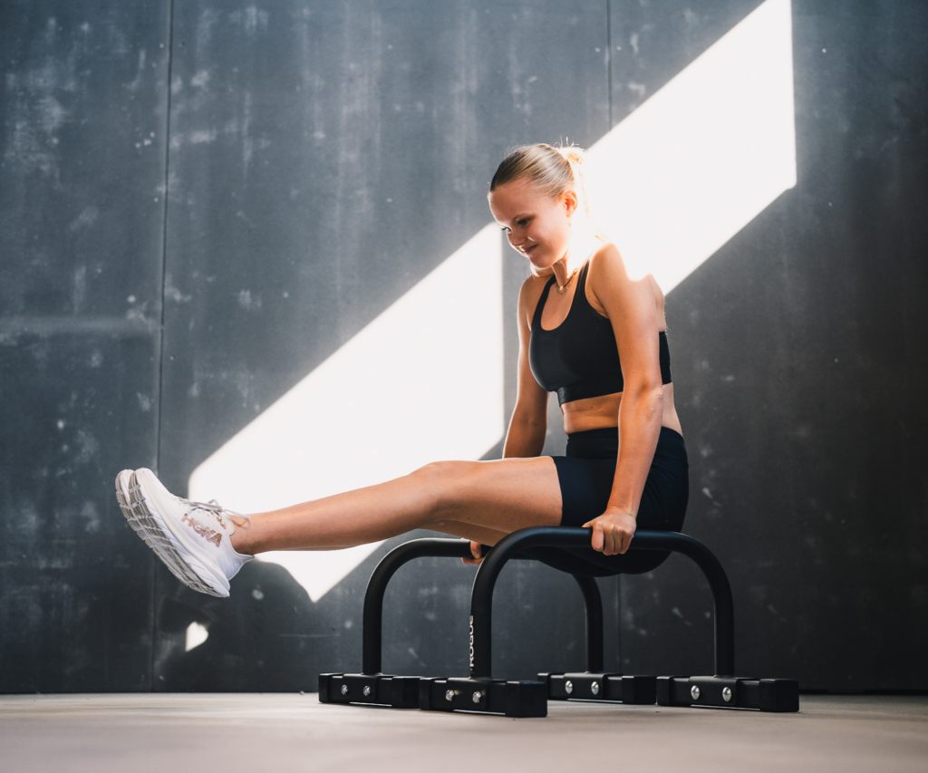 Athlete on parallettes in a sunlit concrete room
